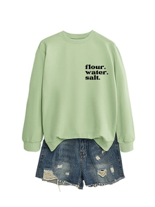 Dettaglio della felpa verde chiaro con stampa e pantaloncini di denim blu