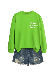 Dettaglio flat lay della felpa verde neon con stampa e pantaloncini di jeans strappati
