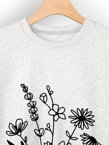 Gros plan d'un sweat gris clair à col rond avec motif floral minimaliste noir imprimé