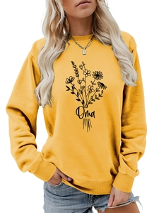 Détail du sweat-shirt jaune moutarde avec art floral linéaire et texte Oma