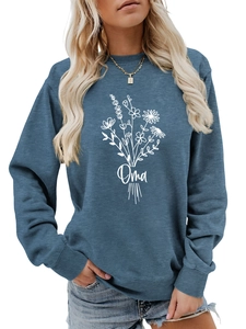 Détail d'un sweat bleu clair avec imprimé bouquet de fleurs blanc et lettrage Oma