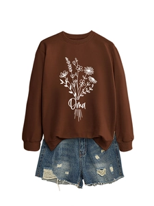Détail du sweat marron ample avec imprimé floral Oma et short en jean bleu à déchirures