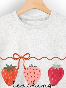Close-up of light grey sweatshirt with teaching is my jam strawberry graphic on wooden hanger