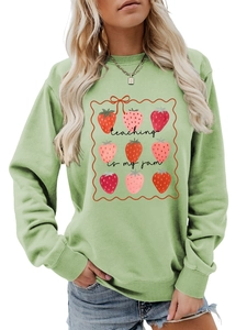 Detail of light green sweatshirt featuring strawberry grid print and teaching is my jam text