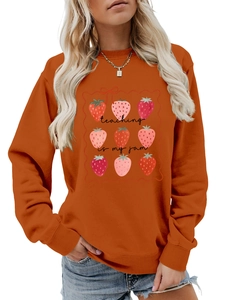 Detail of Teaching is My Jam slogan and strawberry grid print on an orange sweatshirt