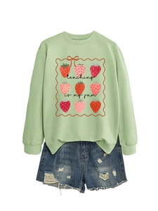 Detail of light green sweatshirt with strawberry print and 'teaching is my jam' text