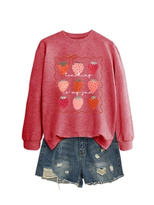 Flat lay of red sweatshirt with strawberry graphics and ripped denim shorts