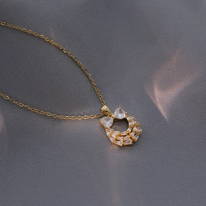 Elegant gold bow wreath necklace with sparkling cubic zirconia on silk fabric background