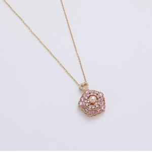 Detailed macro of a rose gold floral pendant with pink cubic zirconia and freshwater pearl
