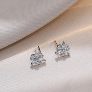 Silver clover stud earrings with marquise zircon stones on champagne silk background