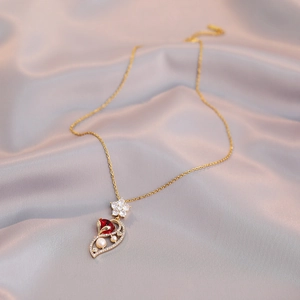 Elegant gold necklace with a red pear-cut gemstone, white pearls, and a floral pendant