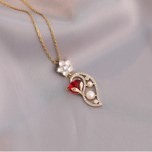 Golden titanium necklace featuring a fox-inspired pearl and red heart gemstone pendant