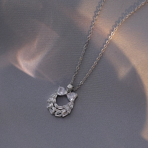 Elegant silver bow and horseshoe necklace with pavé zircons on gray fabric background