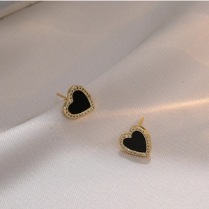 Elegant gold heart earrings with black enamel and zircon crystals on white silk