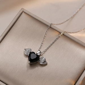 Collier élégant avec pierre noire en forme de cœur et ailes d'ange sur boîte à bijoux