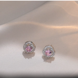 Elegant pink zircon stud earrings with silver-toned floral setting on silk background