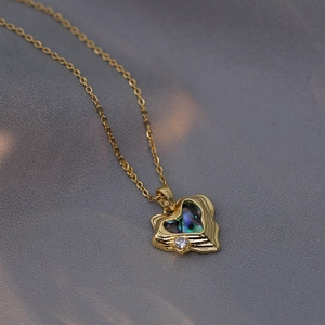 Golden heart necklace with iridescent shell inlay and zircon on grey silk backdrop