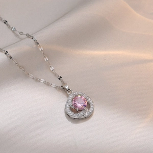 Collier avec pendentif fleur en zircon rose et chaîne en acier argenté sur satin blanc