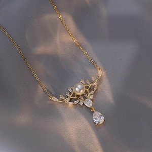Elegant gold necklace with white pearl and marquise zircon pendant on dark silk