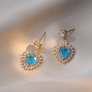 Golden heart earrings with blue zircon center and marquise crystals on white silk