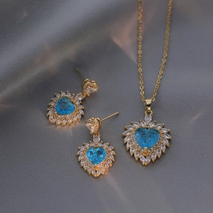 Golden jewelry set with heart-shaped blue zircon pendant and matching earrings