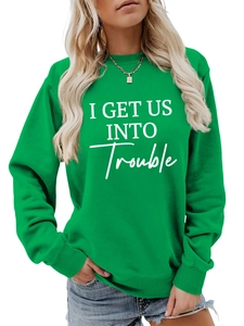 Detail eines grünen Sweatshirts mit weißem I GET US INTO Trouble Schriftzug