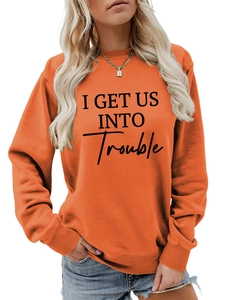 Detailaufnahme des I GET US INTO TROUBLE Slogan-Prints auf orangefarbenem Sweatshirt