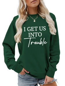 Detail eines lockeren dunkelgrünen Sweatshirts mit I GET US INTO TROUBLE Aufschrift