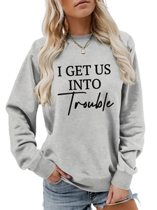 Detail eines grauen Sweatshirts mit I Get Us Into Trouble Aufdruck und gerippten Ärmelbündchen