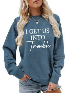 Detail eines blauen Sweatshirts mit weißem I GET US INTO TROUBLE Buchstaben-Aufdruck