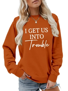 Detail eines karamellfarbenen Sweatshirts mit I Get Us Into Trouble Aufdruck in Weiß