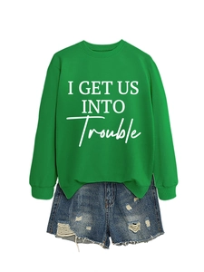 Detail eines grünen Langarm-Sweatshirts und zerfetzten Denim-Shorts mit Slogan-Druck