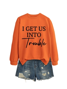 Detail eines orangefarbenen Sweatshirts mit schwarzem I GET US INTO TROUBLE Textaufdruck