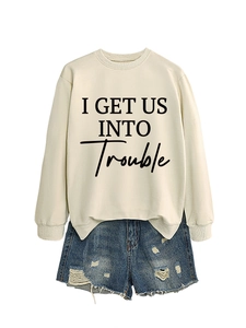 Detail eines beigen Sweatshirts mit I GET US INTO TROUBLE Aufdruck und Rippbündchen am Hals