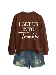 Detail eines lockeren dunkelbraunen Sweatshirts mit Textprint und zerrissenen Denim-Shorts