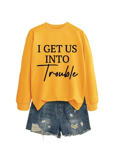 Detail eines gelben Sweatshirts mit schwarzem Schriftzug und destroyed Denim-Shorts
