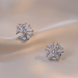 Vue macro détaillée de boucles d'oreilles fleurs en zircon sur tissu de soie champagne