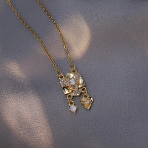 Collier en or rose avec pendentif fleur en zircone et pampille élégante sur fond texturé