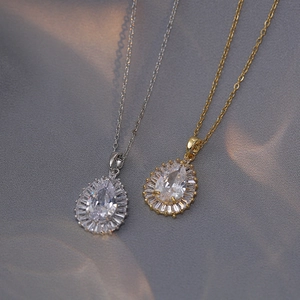 Halskette mit Wassertropfen-Zirkonia in Gold und Silber auf seidigem Stoff