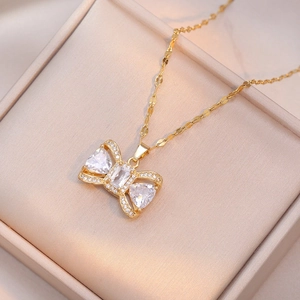 Elegant gold bow necklace with white zircon center on champagne silk jewelry gift box
