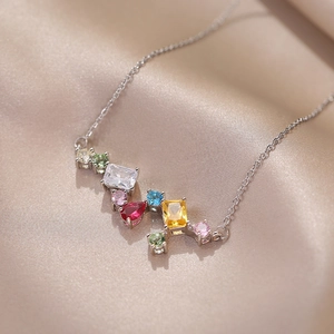 Collar de plata brillante con circonitas de colores sobre fondo de seda color champán