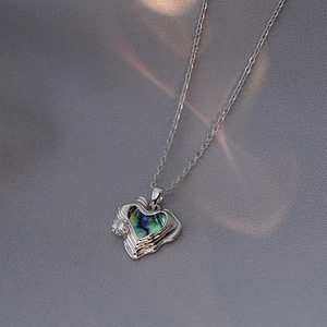 Macro view of heart pendant featuring iridescent shell inlay and sparkling zircon detail