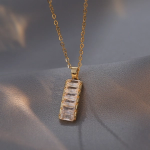 Elegant gold necklace with vertical baguette-cut zircon pendant on silk background