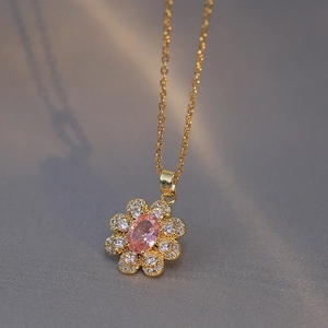 Elegant gold flower necklace with pink zircon center and sparkling white stones on grey stone