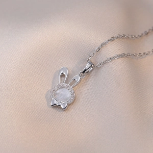 Détail macro d'un pendentif lapin argenté avec incrustation de nacre et zircons