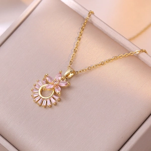 Collier élégant en acier titane doré avec pendentif fleur en zircon rose sur velours beige