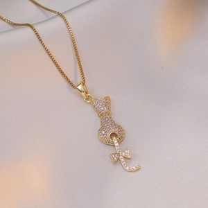 Golden cat pendant necklace with pink cubic zirconia on soft white silk background