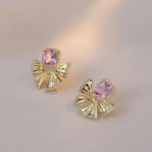 Elegant gold bow earrings featuring a pink rectangular crystal and micro-pave zirconias