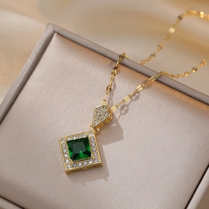 Golden titanium necklace with square emerald zircon pendant on a beige jewelry box