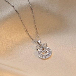 Elegant silver bow zircon circular pendant necklace on champagne satin silk background